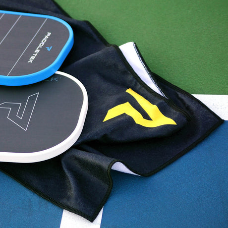 Paddletek Performance Towel with yellow logo on a pickleball court